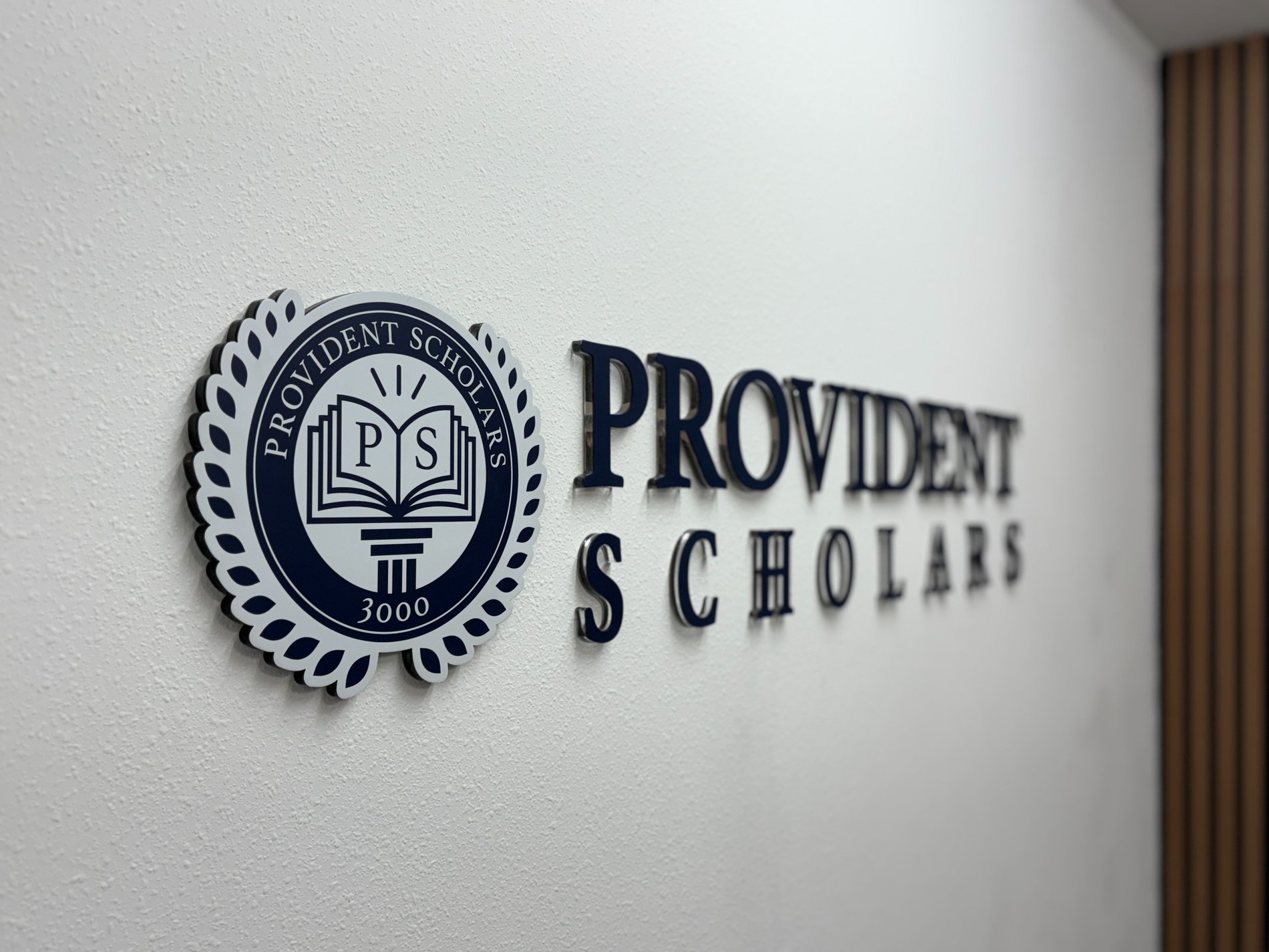 Provident Scholars wall emblem showing the open book, pillar, and 3000